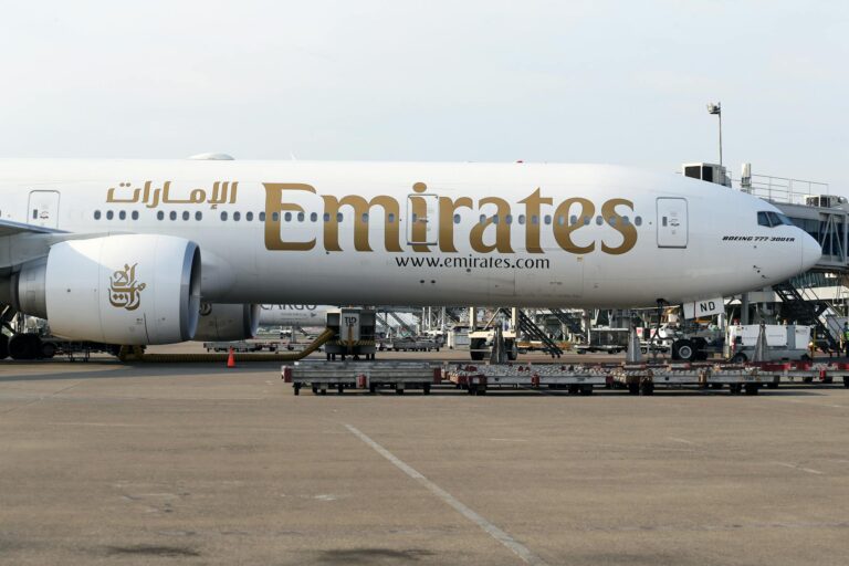 Emirates Boeing 777 on the tarmac during day at a bustling airport.
