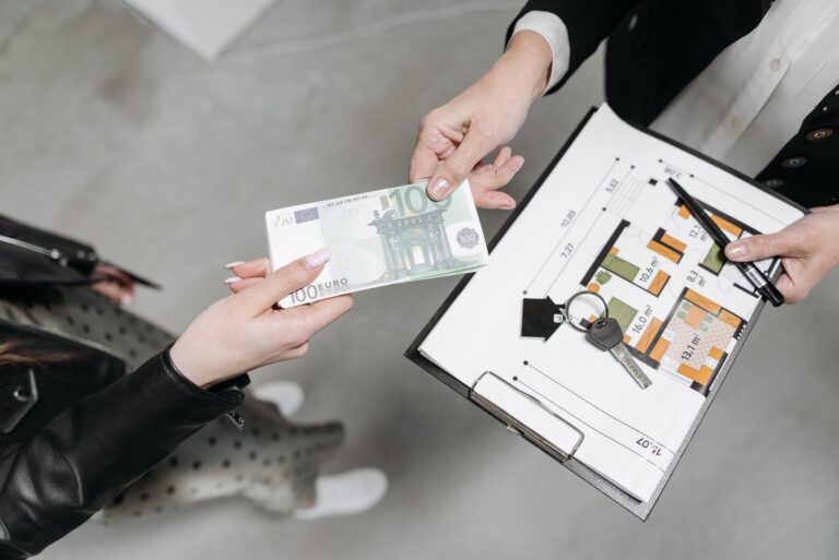 Close-up of a real estate transaction with euro bill, keys, and floor plan.