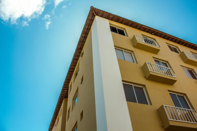 Close-up of a yellow residential building facade against a clear blue sky.
