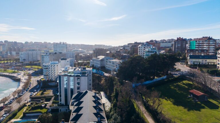 Aerial cityscape of Santander, Spain, featuring coastal buildings and scenic landscapes under a sunny sky.