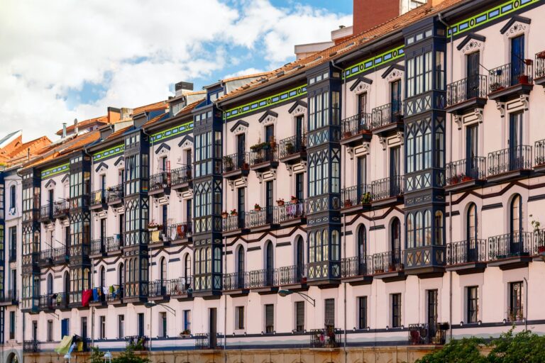 Charming European apartment facade featuring unique patterns and vibrant colors under a bright sky.