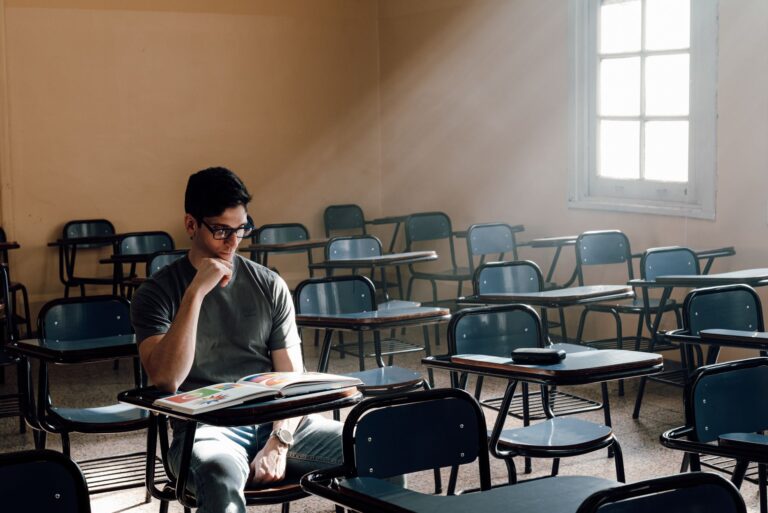 A person studies alone in an empty classroom with sunlight streaming through the window in Buenos Aires.